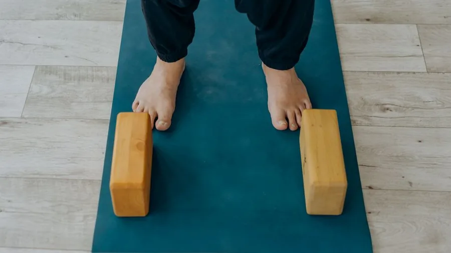 매트 위에 맨발로 선 발과 요가 블록