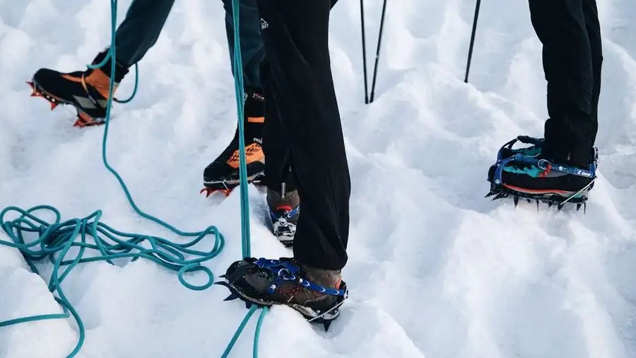 아이젠을 신고 눈 쌓인 산을 오르는 등산객들의 발